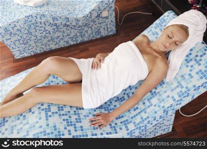 young beautiful woman relaxing at spa and wellness center at hot bed with blue tiles decoration