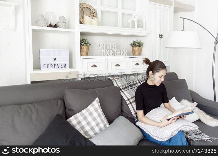 Young beautiful woman relaxing on sofa at home and reading a book