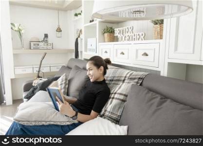 Young beautiful woman relaxing on sofa at home and reading a book