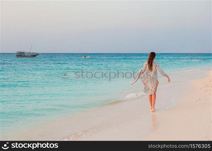 Young beautiful woman relaxing on the beach at sunset. Woman laying on the beach enjoying summer holidays