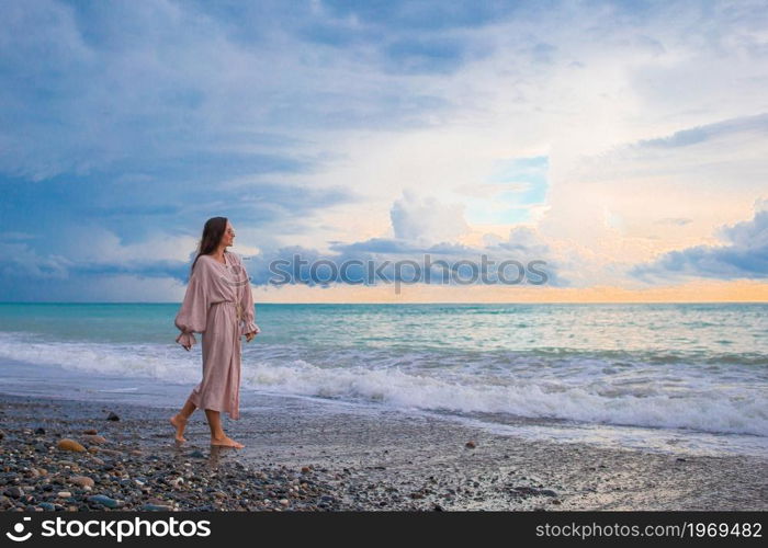 Young beautiful woman relaxing on the beach at sunset. Woman laying on the beach enjoying summer holidays looking at the sea