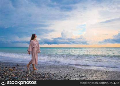Young beautiful woman relaxing on the beach at sunset. Woman laying on the beach enjoying summer holidays looking at the sea