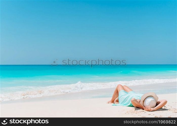 Young beautiful woman relaxing on the beach. Woman laying on the beach enjoying summer holidays looking at the sea