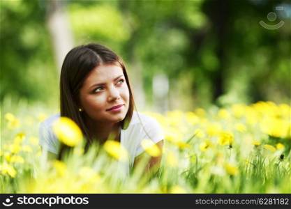 Young beautiful woman resting on fresh green grass with flowers