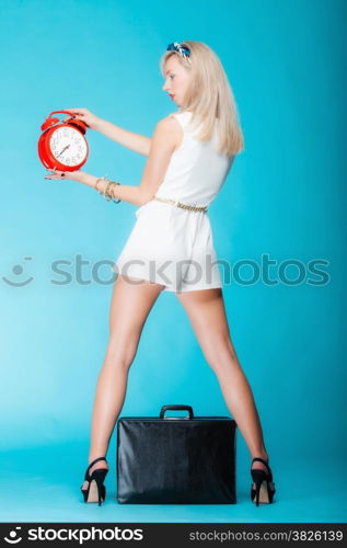 Young beautiful woman sexy girl with suitcase red clock on vivid blue blue background. Travel time management concept