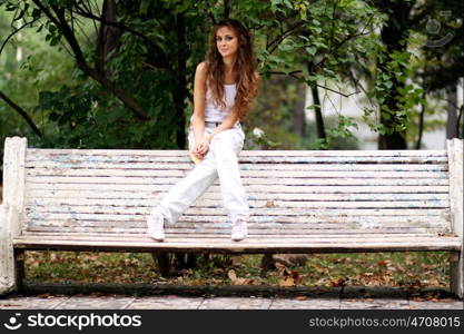 Young beautiful woman sitting on a bench in autumn park