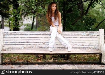 Young beautiful woman sitting on a bench in autumn park