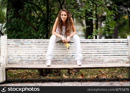 Young beautiful woman sitting on a bench in autumn park