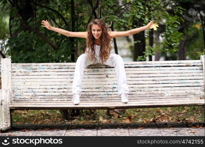 Young beautiful woman sitting on a bench in autumn park