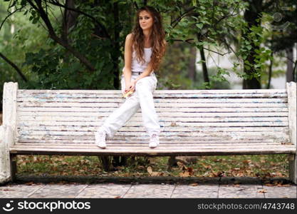 Young beautiful woman sitting on a bench in autumn park