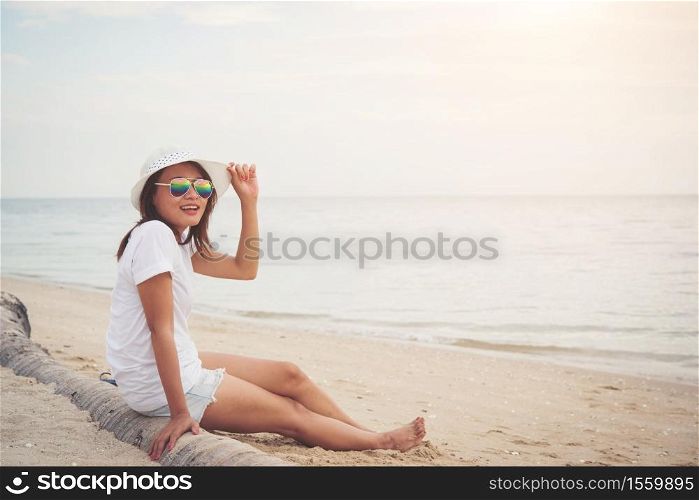 Young beautiful woman sitting on the beach wearing sunglasses. Freedom enjoy holiday, Women lifestyle concept.