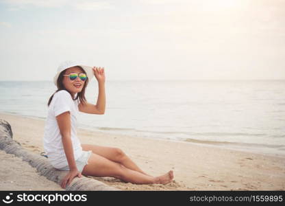 Young beautiful woman sitting on the beach wearing sunglasses. Freedom enjoy holiday, Women lifestyle concept.