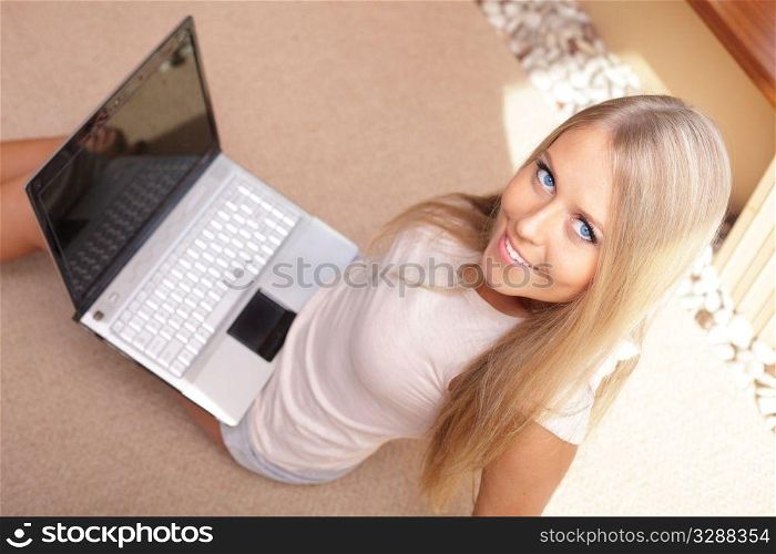 Young beautiful woman sitting on the floor and working on a laptop