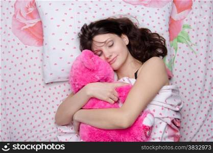 Young beautiful woman sleeping in bed with teddy bear