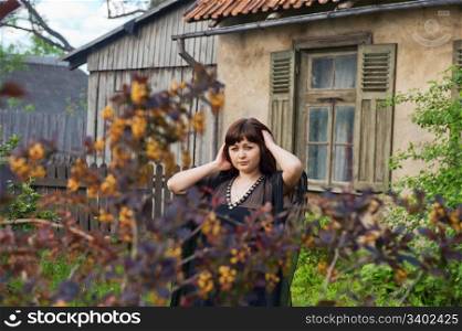 Young beautiful woman stand in the garden nearby old house.