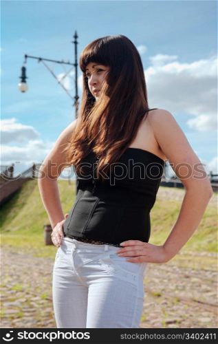 Young, beautiful woman stand with hands in line with the seam of the trousers.