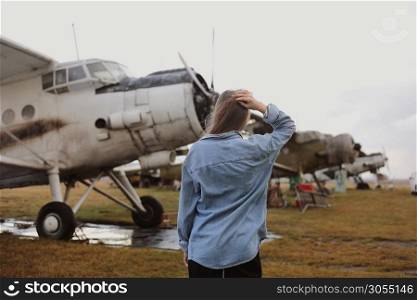 young beautiful woman standing near the plane. Traveling and technology. back view.. young beautiful woman standing near the plane. Traveling and technology. back view