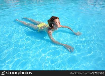 young beautiful woman swimming in yellow bikini in paddling pool