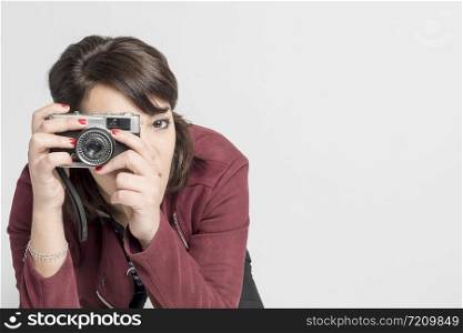 Young beautiful woman taking a photo with a retro camera