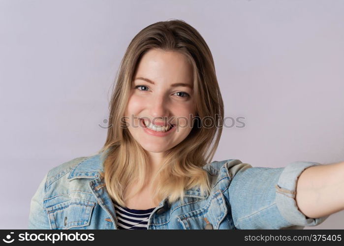 Young beautiful woman taking selfie in a studio. Isolated white background.