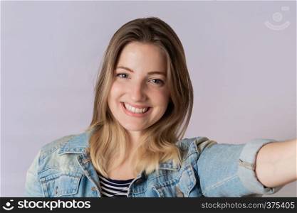 Young beautiful woman taking selfie in a studio. Isolated white background.