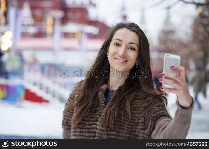 Young beautiful woman tourist taking pictures on mobile phone on the background Red Square, Moscow Kremlin, Russia