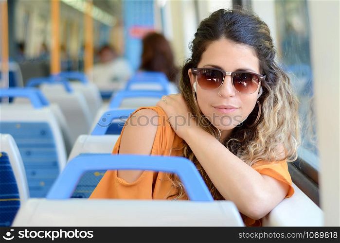 Young beautiful woman tourist traveling by the train sitting near the window. Enjoying travel concept.