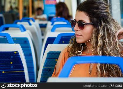 Young beautiful woman tourist traveling by the train sitting near the window. Enjoying travel concept.