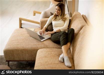 Young beautiful woman using a laptop on the sofa at home