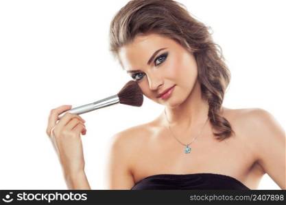 Young beautiful woman using a make-up brush, isolated on white