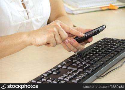 Young beautiful woman using her cell phone in office