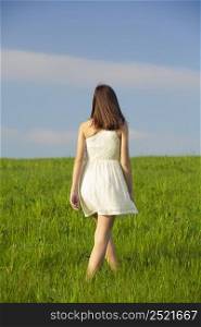 Young beautiful woman walking on a green meadow
