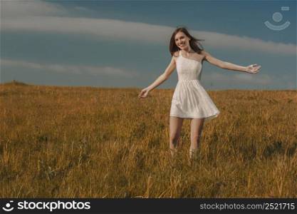 Young beautiful woman walking on a meadow wearing a white dress