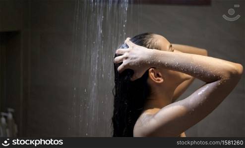 Young beautiful woman washing her hair in a bathroom at home