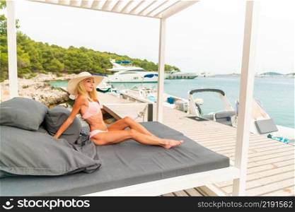 young beautiful woman wearing hat and pareo sitting on sunbed - Croatia. young beautiful woman wearing hat and pareo sitting on sunbed
