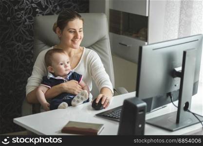 Young beautiful woman with 9 month baby working at home
