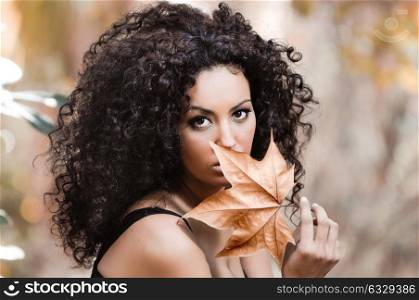 Young beautiful woman with a dry leaf in an urban park