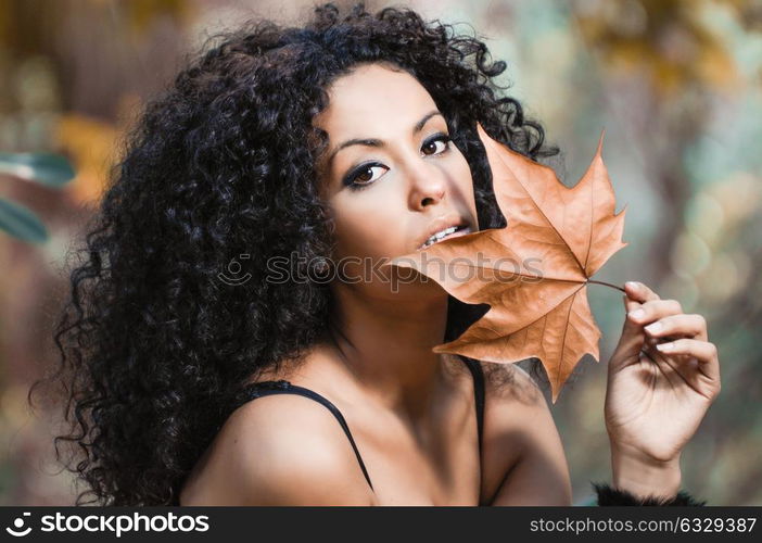 Young beautiful woman with a dry leaf in an urban park