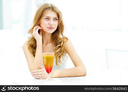 Young beautiful woman with a glass of drink sitting in a cafe