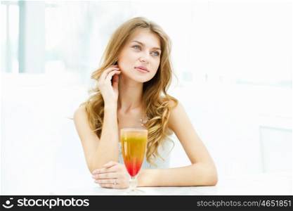 Young beautiful woman with a glass of drink sitting in a cafe