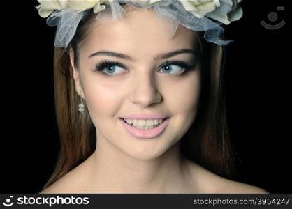 Young beautiful woman with a wreath of flowers, isolated on black, image was slightly toned