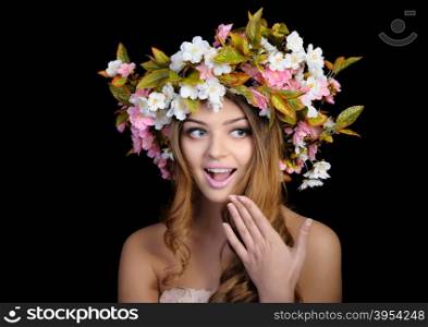 Young beautiful woman with a wreath of spring flowers, isolated on black
