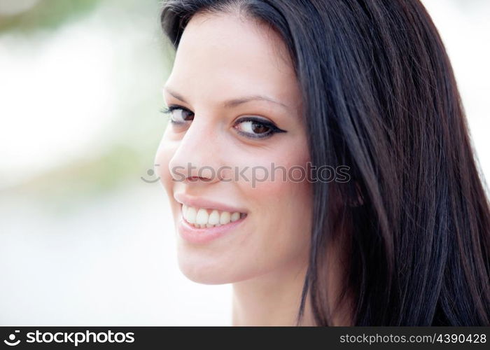 Young beautiful woman with brunette hair and perfect smile posing in park