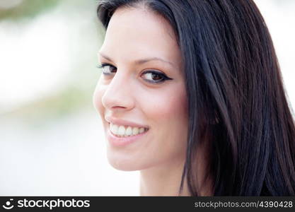 Young beautiful woman with brunette hair and perfect smile posing in park