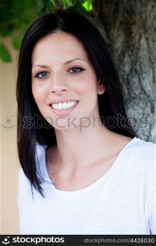 Young beautiful woman with brunette hair and perfect smile posing in park