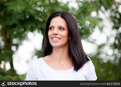 Young beautiful woman with brunette hair and perfect smile posing in park