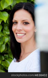 Young beautiful woman with brunette hair and perfect smile posing in park