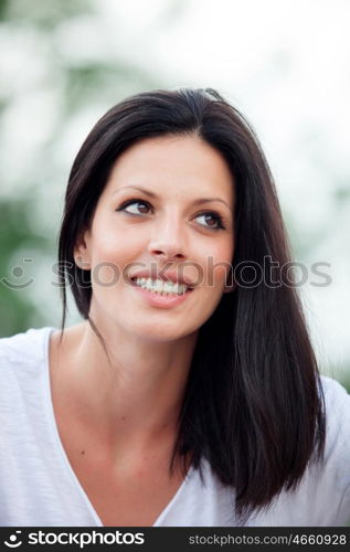 Young beautiful woman with brunette hair and perfect smile posing in park