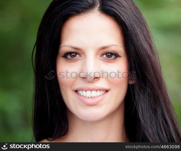 Young beautiful woman with brunette hair and perfect smile posing in park