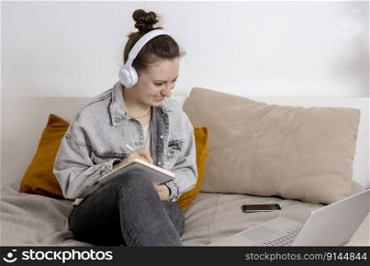 Young beautiful woman with casual clothes sitting on the bed at home with laptop computer and studying. Girl using e-learning platform to make a video call with her teacher. Distance education. Young beautiful woman with casual clothes sitting on the bed at home with laptop computer and studying. Girl using e-learning platform to make a video call with her teacher. Distance education.